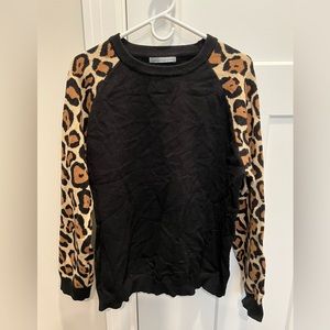 Black sweater with leopard print sleeves.